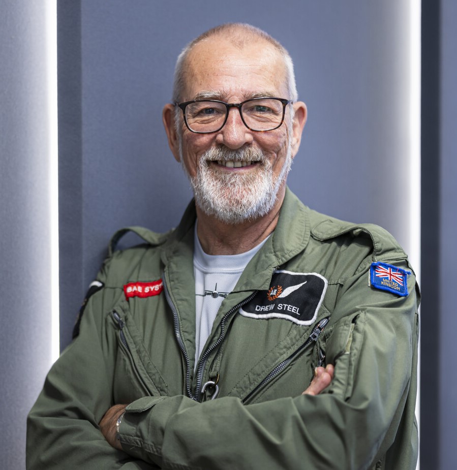 Drew with arms folded, smiling at the camera